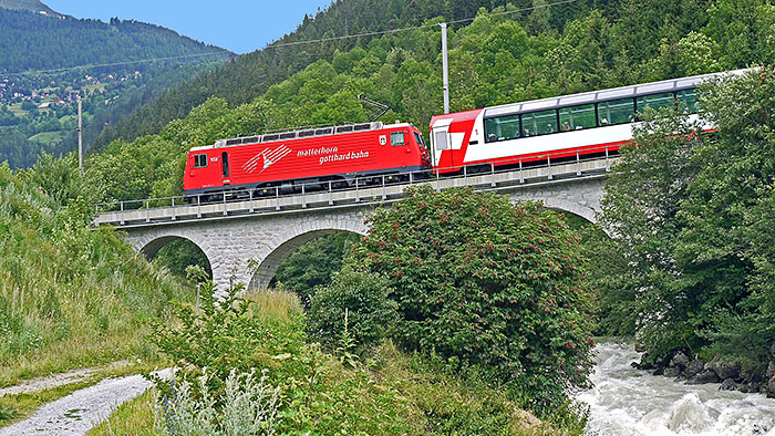 Glacier-Express fährt über eine steinerne Brücke
