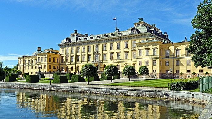 Residenzschloss Drottningholm in hellgelber Fassade ist UNESCO-Welterbestätte auf der Insel Lovön in Schweden